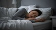 © Agus Through Lens - A beautiful young woman sleeping soundly and peacefully in a comfortable bed with soft white pillows and a duvet in a dark bedroom at night