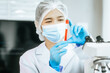 © Thitaporn - An Asian female scientist carefully analyzes microscopic samples and chemical solutions in a modern laboratory, conducting biology, microbiology, pharmaceutical, and medical research with precision