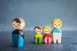 © sommart - Symbolic wooden figures representing family separation and divorce. One smiling figure stands apart from a sad mother and children, reflecting emotional impact and broken family dynamics.