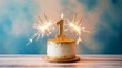 © Kage Dojo - A festive birthday cake with a golden '1' candle and sparklers, set against a soft blue background, perfect for celebrating a first birthday.