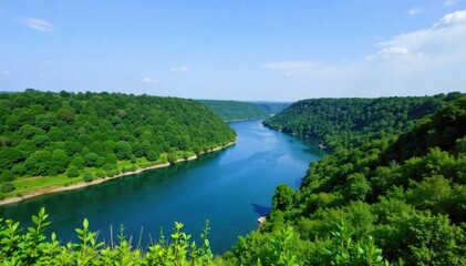 Naklejka na meble Flowing River Through Lush Landscape A wide, clear river with gentle curves flowing through a lush, vibrant green valley. Rolling hills covered in dense foliage surround the river. The sky is bright