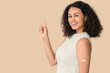 © Pixel-Shot - Beautiful young happy African-American woman with applied medical patch pointing at something on beige background