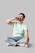 © Pixel-Shot - Young man with modern mobile phone sitting on grey background