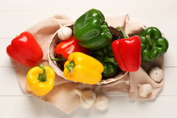 Wall Mural - Wicker bowl with fresh colorful bell peppers and garlic on white wooden background