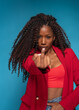 © Renata Hamuda - African american woman in red jacket and curly hair showing middle finger gesture on blue background