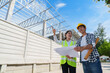 © crizzystudio - Construction engineers reviewing building plans at site