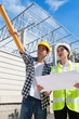 © crizzystudio - Construction workers discussing project while pointing at building