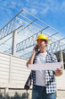 © crizzystudio - Engineer talking on phone holding blueprint on construction site