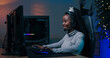 © ABCreative - A skilled female player sits in front of the computer, coordinating with her team through a microphone. She smiles contentedly while concentrating on strategy during the game.
