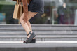 © crizzystudio - Woman experiencing leg pain while carrying shopping bags
