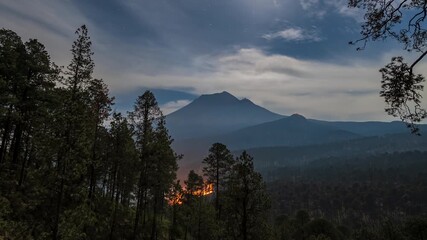 Wall Mural - Timelapse of an active forest fire at Volcán Popocatépetl during the night, illuminated by a full moon and dramatic skies.