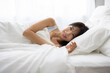 © hidez - Smiling Young Woman Lying in Bed and Waking Up in the Morning
