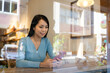 © leungchopan - Woman looking at phone inside cafe with window reflection