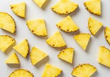 Fresh yellow pineapple wedges and slices arranged on a clean white background from a top-down view.