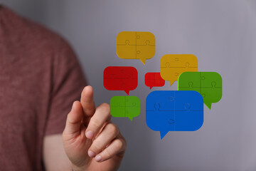 conceptual image symbolizing teamwork. man interacting with speech bubbles made of puzzle pieces ind