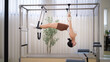 © wattana - Fit woman performing horizontal inversion stretch on a Pilates Cadillac reformer, showing strength and precision.