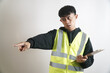 © yashis007 - Construction Worker Directing with Authority Pointing and Holding Clipboard in Studio Shot