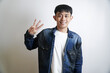 © yashis007 - Young Asian man smiling and holding up three fingers against a white background