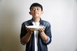 © yashis007 - A man holds an empty plate while closing his eyes, as if smelling the delicious aroma of food.