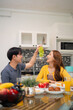 © Pichsakul - Adult Asian couple enjoying healthy breakfast home kitchen sharing fresh fruits dining table relaxed morning happy lifestyle wellbeing togetherness