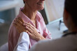 © DragonImages - Middle aged Caucasian woman sitting in medical office receiving comforting touch from female doctor during cancer consultation, both women partially visible, focus on supportive gesture