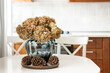 © svetlana_cherruty - Autumn bouquet of dry hydrangea in vase and pine cone at white kitchen. Cozy home interior with season decoration. Close up.