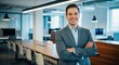 © Meow Creations - Confident young businessman smiling with arms crossed in a modern corporate office