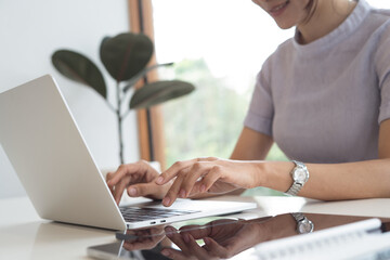 Wall Mural - Casual business woman online working on laptop with digital tablet on table, surfing the internet, online work, closeup. Woman hand typing on laptop computer keyboard on office table at home.