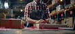 © Panachev E - A man in an apron sits at a table taping a cardboard box, with shelves of goods storage visible in the warehouse background.