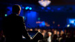 © shan - seminar. A professional speaker addressing an audience at a corporate event with stage lighting. pitch deck slides.