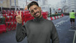 © Krakenimages.com - Man makes peace sign with both hands and smiles broadly on busy sunlit urban construction site; optimism.