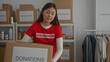 © Krakenimages.com - Woman volunteering in charity room organizes donation boxes among clothes and supplies showcasing generosity and community spirit.