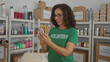 © Krakenimages.com - Woman in green volunteer shirt using smartphone indoors surrounded by donation boxes in a charity room showing engagement and community spirit.
