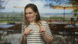 © Krakenimages.com - Woman in striped shirt grimaces with clenched fists and scrunched nose on sunlit restaurant terrace outdoors; disgust.