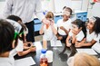 © Rawpixel.com - Diverse group of children in a science class, wearing safety goggles, excitedly watching a teacher demonstrate an experiment with colorful liquids in a lab. Diverse young students in science class.