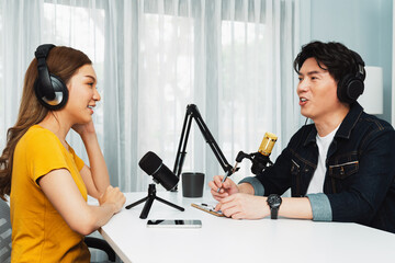 Smiling radio influencer host wearing headphone interviewing woman speaker sharing information to listeners on social media online website live streaming channel at morning at studio record. Infobahn.