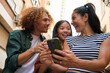 © Ladanifer - Group of young tourists using smartphone and laughing in the street