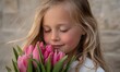 © simba kim - A young girl with blonde hair, highlighted with delicate glitter, is captured in a moment of pure bliss as she brings a vibrant bouquet of pink tulips to her face