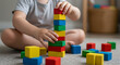 © Shati - A child is playing with colorful wooden building blocks, stacking them into a tower, fostering creativity and developing fine motor skills