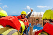 © Mariusz - Deck officer wearing a yellow hard hat and orange life jacket demonstrates life raft deployment on a merchant ship.