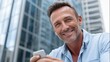 © liliyabatyrova - A cheerful man stands against a backdrop of modern buildings, holding his phone. He appears relaxed and happy, enjoying the moment in the vibrant city atmosphere