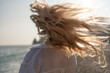 © svetograph - Hair wind beach. Blonde woman's flowing hair blows wildly by the ocean at sunset, evoking feelings of freedom and natural beauty