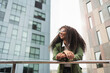 © EFStock - Young African American business woman in trendy outfit and glasses standing in corporate urban district. Inspired creative female professional looking away in the city