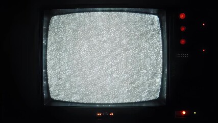 An old, black television displays static on its screen, with red indicator lights