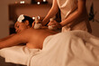 © Pixel-Shot - Young African-American woman getting massage with herbal bags in dark spa salon