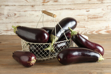 Wall Mural - Basket with fresh eggplants on wooden background
