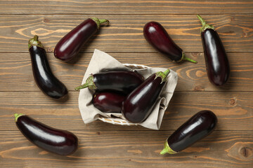 Wall Mural - Basket with fresh eggplants on wooden background
