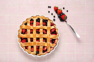 Wall Mural - Baking dish with tasty berry pie and spatula on pink tile background