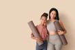 © Pixel-Shot - African-American mother with her teenage daughter and yoga mats hugging on beige background