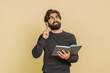 © Andrii Iemelianenko - Thoughtful young Indian businessman making notes, writing down thoughts with pen into notepad notebook diary, to do list, good idea. Hispanic adult guy isolated on beige studio background indoors